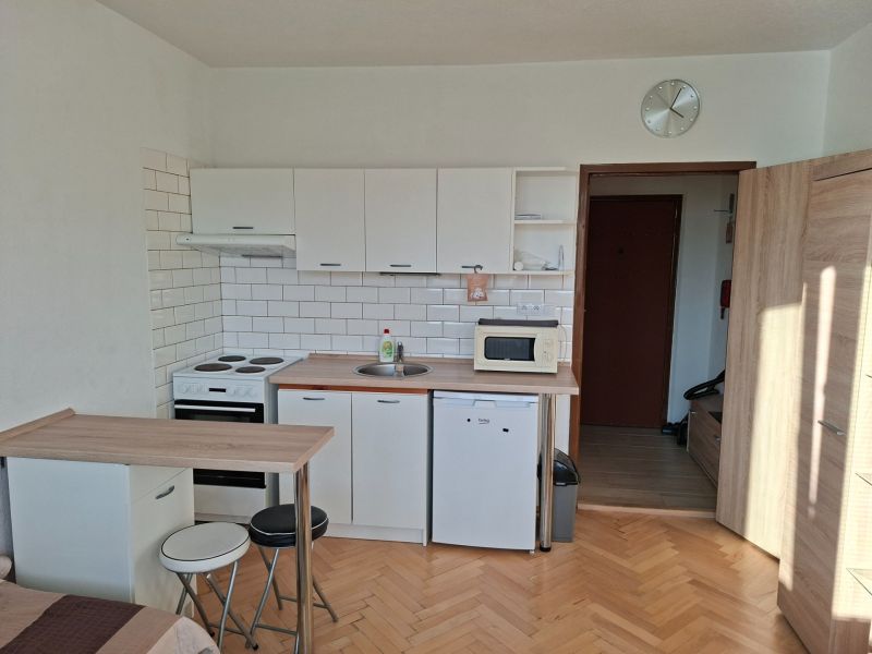 Kuchyňský kout s podlahou s dřevěným dekorem v garsonce.