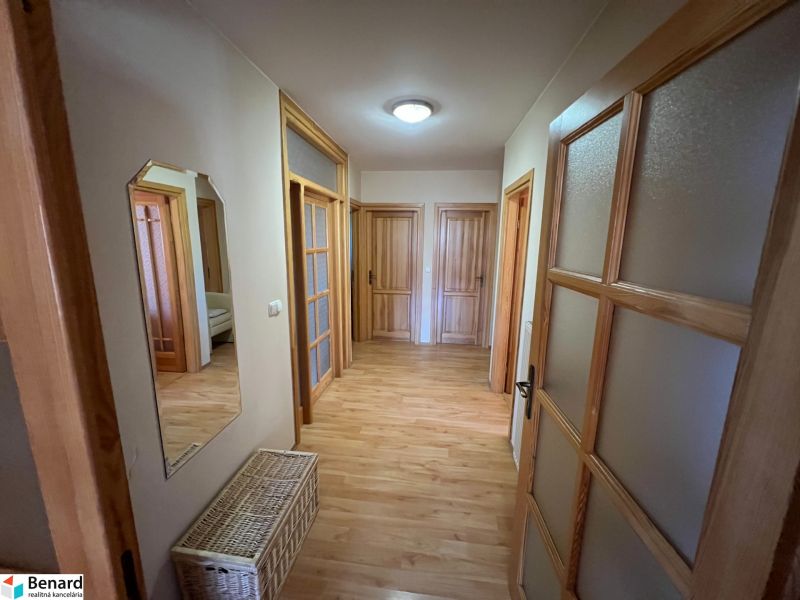 Chodba v rodinném domě s podlahou s dřevěným dekorem a několika dveřmi.