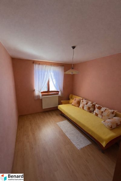 Pokoj s dřevěným dekorem podlahy a pohovkou v rodinném domě.