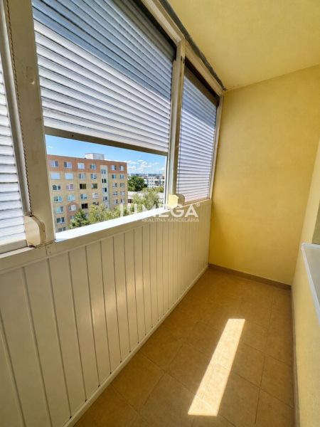 Zasklený balkon s výhledem na paneláky, součást 1-pokojového bytu.
