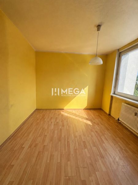 Žlutá místnost s velkým oknem a podlahou s dřevěným dekorem v 3-pokojovém bytě.