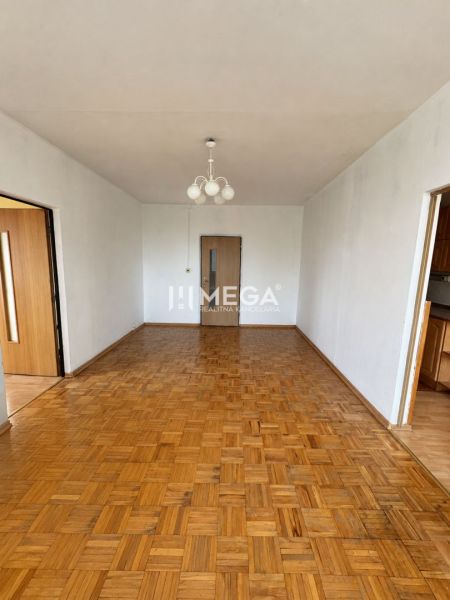 Obývací pokoj v 3-pokojovém bytě s podlahou s dřevěným dekorem a lustrem.