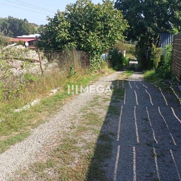 Štěrková cesta vede přes zelené pozemky pro bydlení na ulici v Humenném.