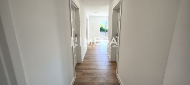 Chodba ve 4-pokojovém bytě, podlaha s dřevěným dekorem, světlé stěny, vstup na balkon.