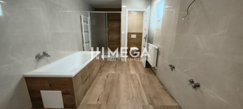 Koupelna s vanou, sprchou a podlahou s dřevěným dekorem ve 4-pokojovém bytě.