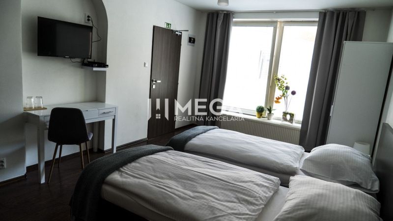 Pokoj v hotelu se dvěma postelemi, televizí a podlahou s dřevěným dekorem.