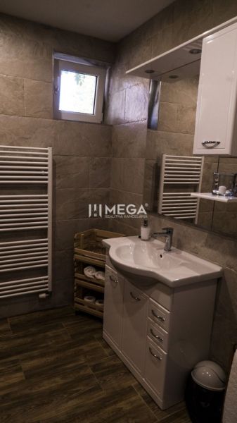 Koupelna s umyvadlem, skříňkou, žebříkovým radiátorem a podlahou s dřevěným dekorem.