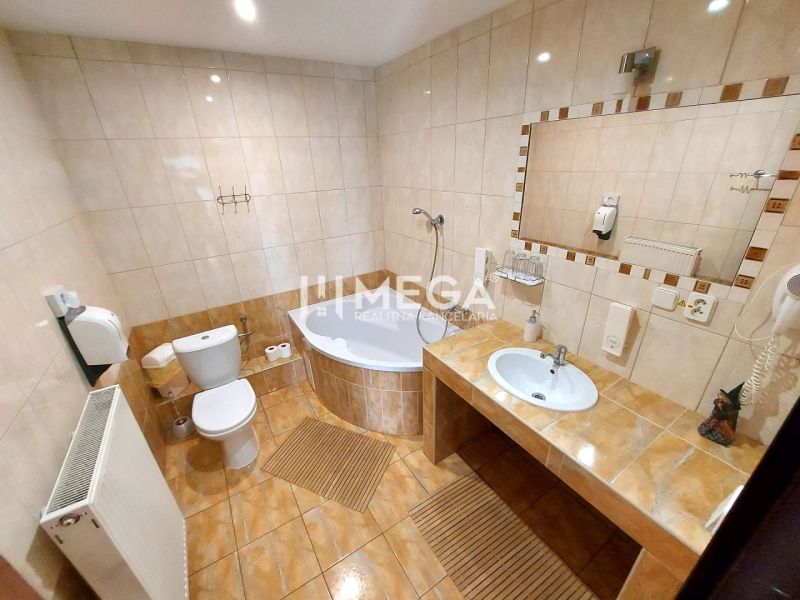 Koupelna v hotelu a penzionu s vanou, toaletou a velkým zrcadlem.