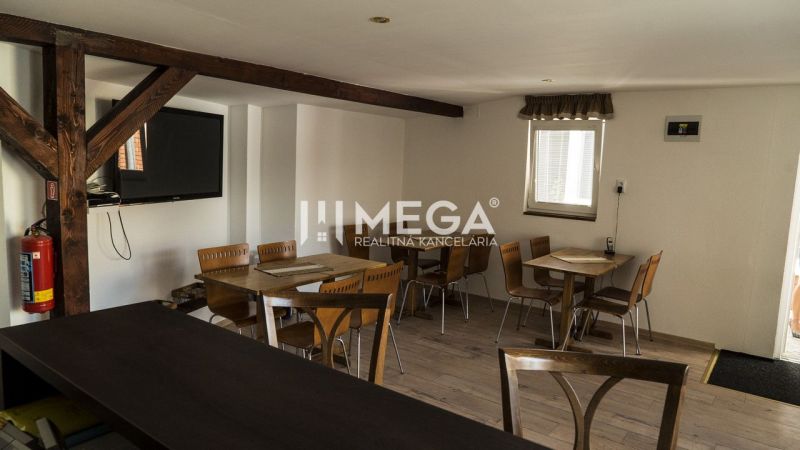 Interiér s dřevěnými trámy, stoly a židlemi v prostorách pro hosty hotelů a penzionů.