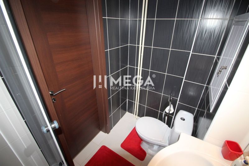 Koupelna v rekreačním apartmánu se sprchovým koutem, toaletou a černými obklady.