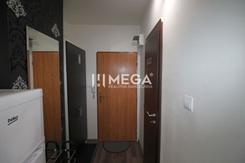 Chodba v rekreačním apartmánu s podlahou s dřevěným dekorem, tapety a lednice.