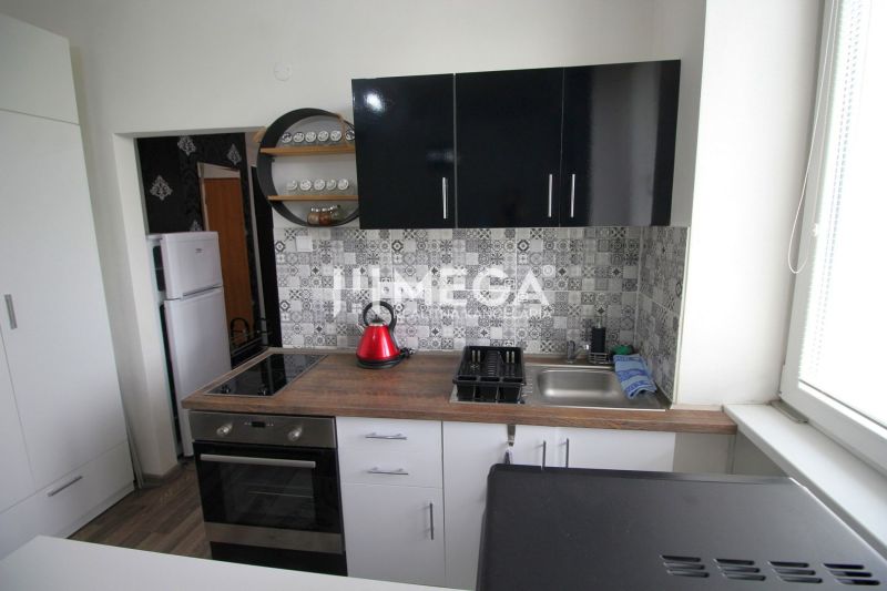 Kuchyně v rekreačním apartmánu s podlahou s dřevěným dekorem a geometrickými obklady na stěně.