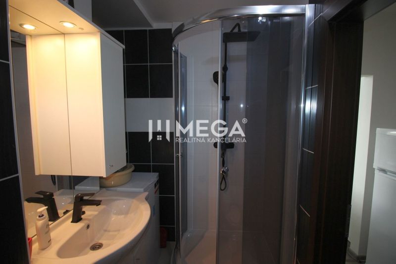 Koupelna v rekreačním apartmánu s umyvadlem, sprchovým koutem a zrcadlem s osvětlením.
