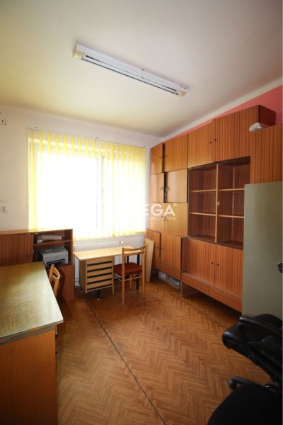 Kanceláře s nábytkem a podlahou s dřevěným dekorem, světlo přes vertikální žaluzie.