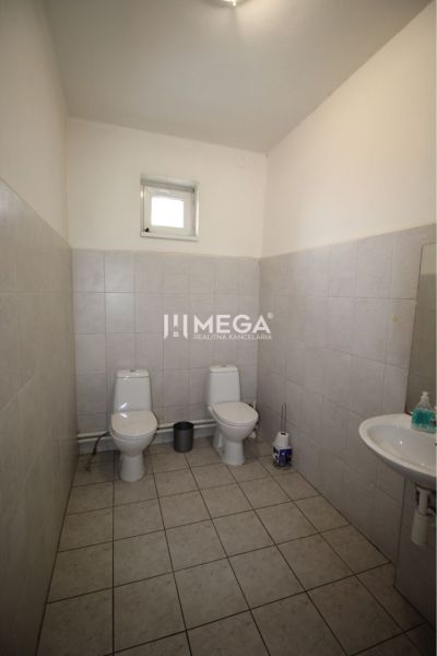 Toaleta v kanceláři se dvěma WC a umyvadlem, obložené bílé kachličky.