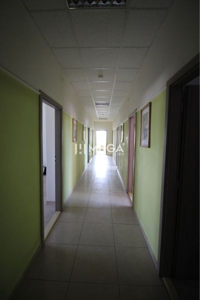 Chodba v kancelářích s bledými stěnami a světlou dlaždicovou podlahou.