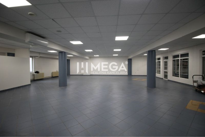 Prostorné obchodní prostory s tmavou dlažbou a podhledovým stropem, vhodné pro podnikání.