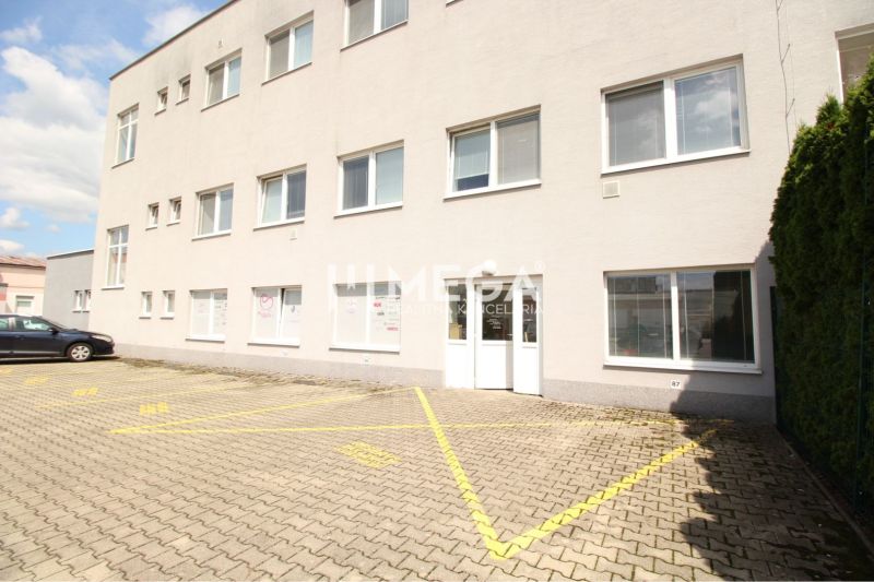 Obchodní prostory na Tolstého ulici v Humenném s parkovacími místy a bílou fasádou.