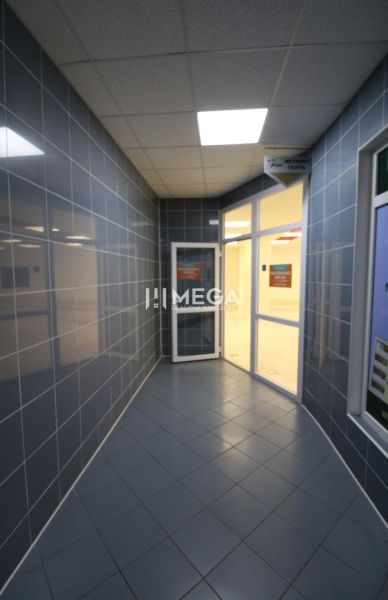 Chodba s dlaždicovou podlahou a prosklenými dveřmi v obchodních prostorách.