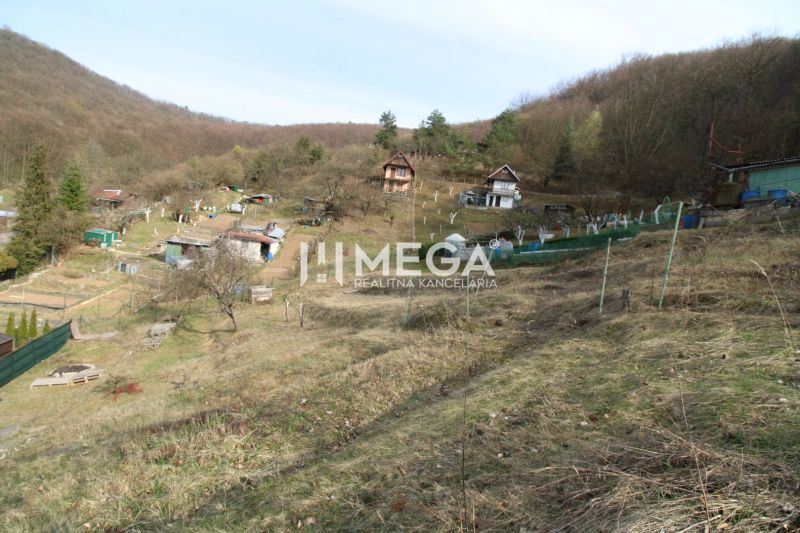 Zahrady na svahu v Humenném v ZO Poniklec s několika dřevěnými chatkami.