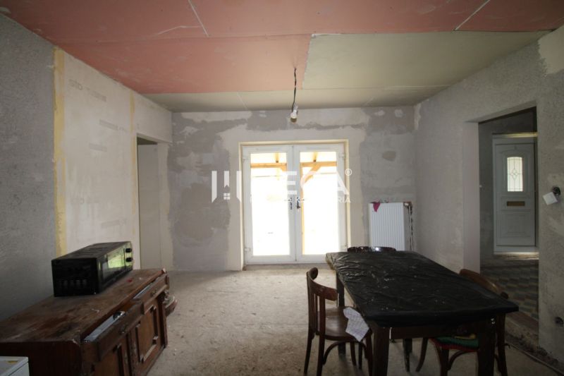 Nedokončený interiér s kuchyňským stolem, židlemi a skříní v rodinném domě.