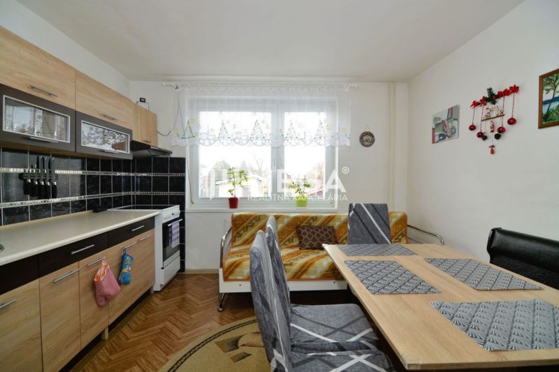 Kuchyně v rodinném domě s kuchyňskou linkou a jídelním stolem, podlaha s dřevěným dekorem.