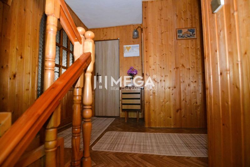 Interiér rodinného domu se schodištěm, dřevěným obkladem a podlahou s dřevěným dekorem.