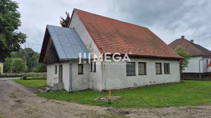 Budova s červenou střechou v Zboji obklopená zelení a sousedními domy, využitelná jako obchodní prostory.