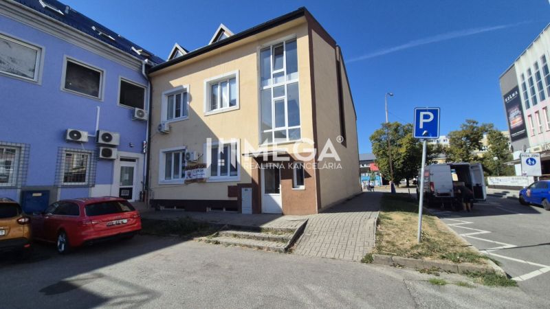Budova s obchodními prostory na Náměstí Svobody v Humenném, před kterou jsou parkovací místa.