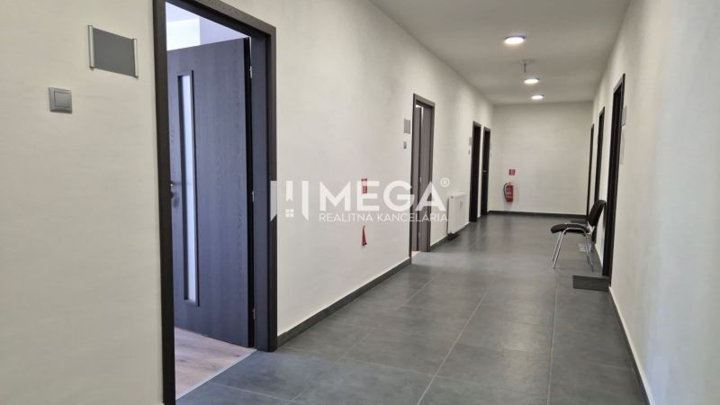 Chodba s několika kancelářemi, dlažbou a otevřenými dveřmi v kancelářích.