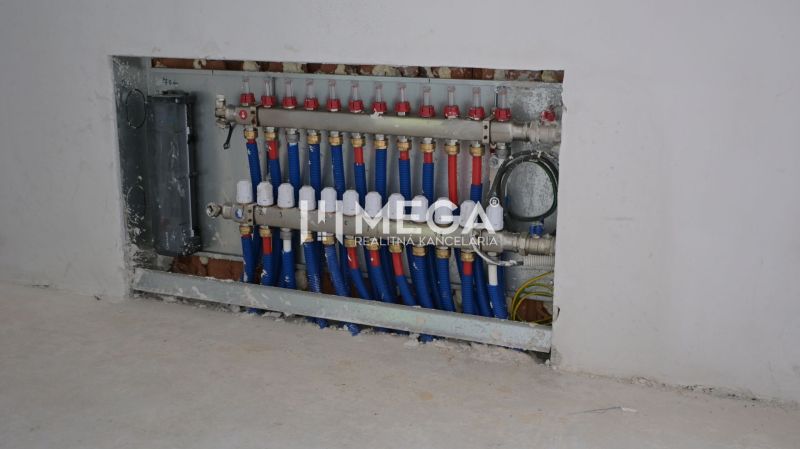 Rozvodná skříň instalací v interiéru rodinného domu s modrými a červenými trubkami.