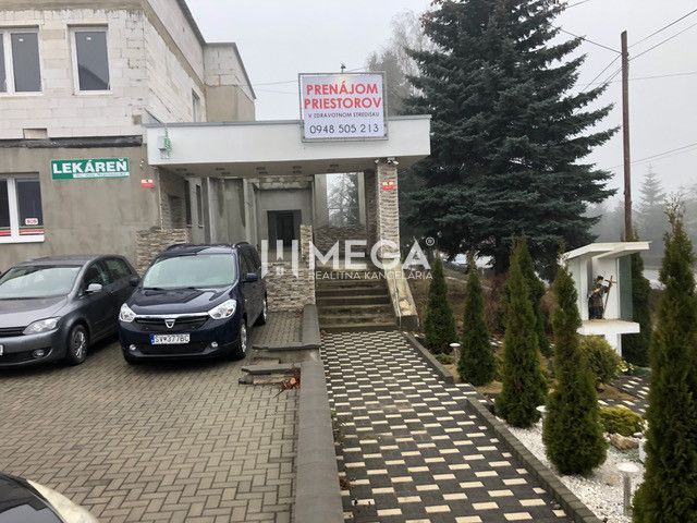 Budova na ulici SNP v Snině s parkovištěm a reklamou na pronájem prostor.