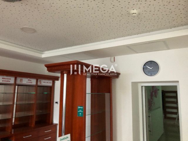 Interiér budovy se skleněnými vitrínami a hodinami na zdi.