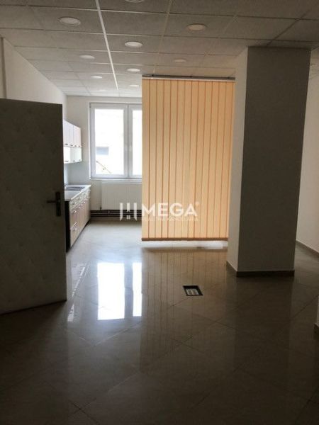Interiér s dlažbou, kuchyňskou linkou a vertikálními žaluziemi v budově.