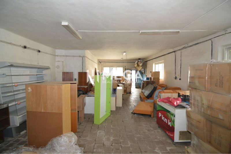 Obchodní prostory s uloženými regály, boxy a zařízením, podlaha s dřevěným dekorem.