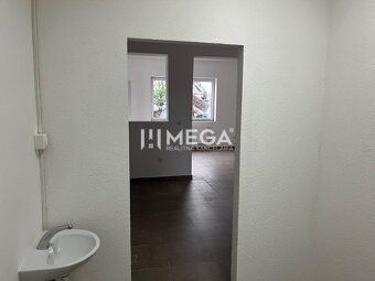 Interiér obchodních prostor s umyvadlem a dveřmi, podlaha s dřevěným dekorem.