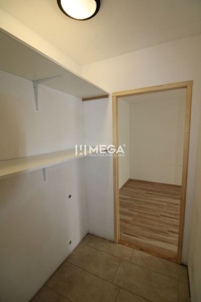 Předsíň s policemi a podlahou s dřevěným dekorem ve 3-pokojovém bytě.