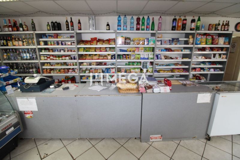 Obchod s potravinami s pultem a regály v rodinném domě, různé produkty na prodej.