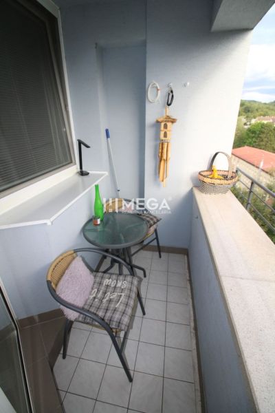 Balkon 2-pokojového bytu s kavárenským stolkem a výhledem na zeleň.