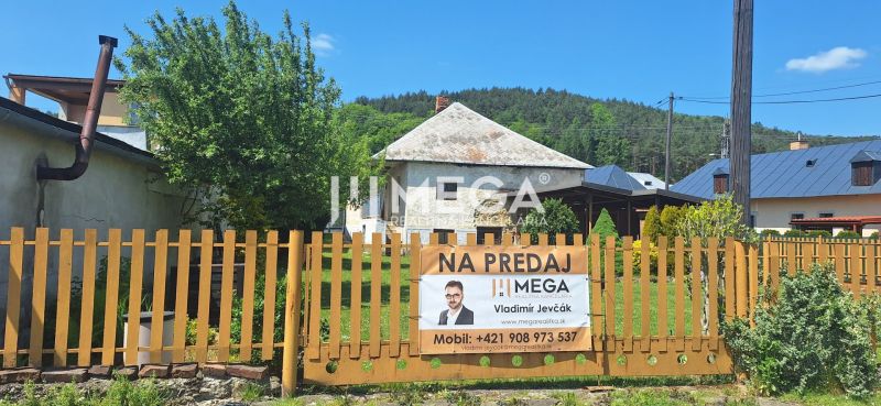 Rodinný dům na prodej v obci Kochanovce stojí za plotem se zelení.
