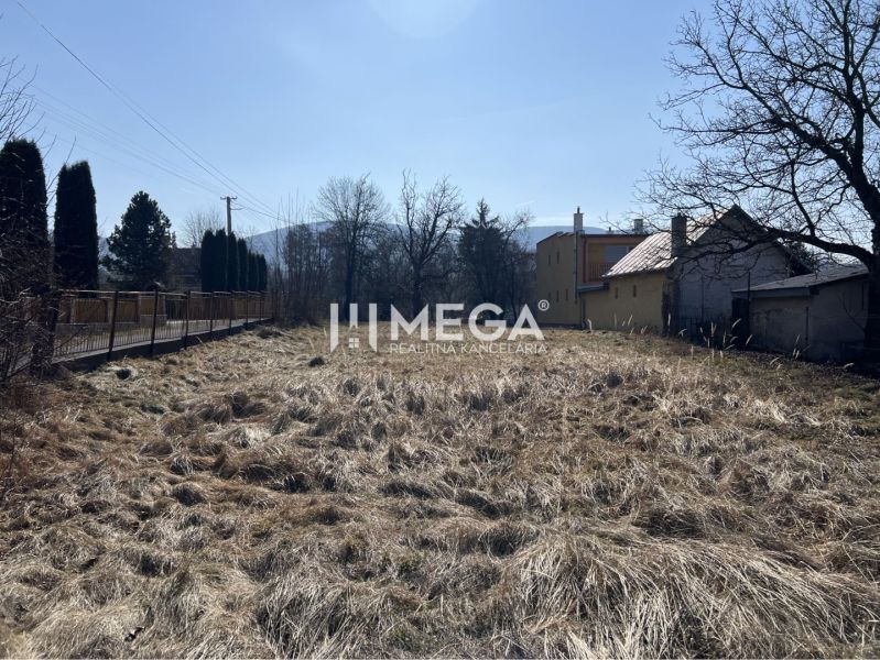 Pozemky - bydlení v Modre nad Cirochou s travnatou plochou a viditelnými budovami.