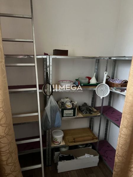 Regály s domácími potřebami v rodinném domě s podlahou s dřevěným dekorem.