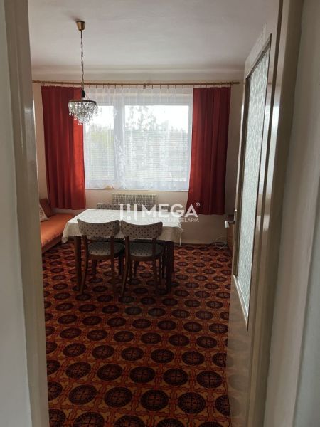 Interiér rodinného domu s kobercem v červeném dekoru, jídelní stůl a lustr.