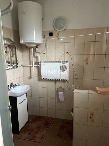 Koupelna s plynovým kotlem a umyvadlem v rodinném domě, dlažba, jednoduché vybavení.