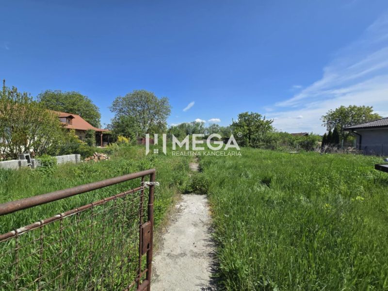 Pozemky - bydlení ve Velké Idě, Gomboši s travnatou plochou a venkovským domem.