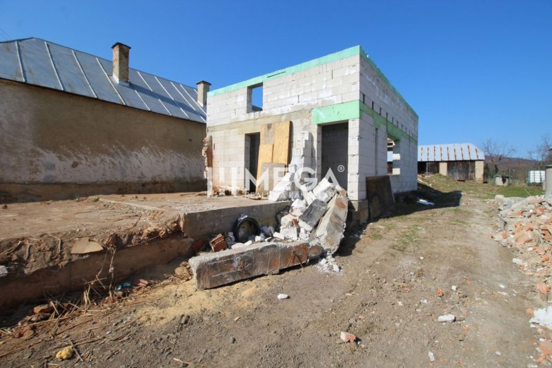Rodinný dům v Zbojném během výstavby s rozestavěnými zdmi a stavebním materiálem.