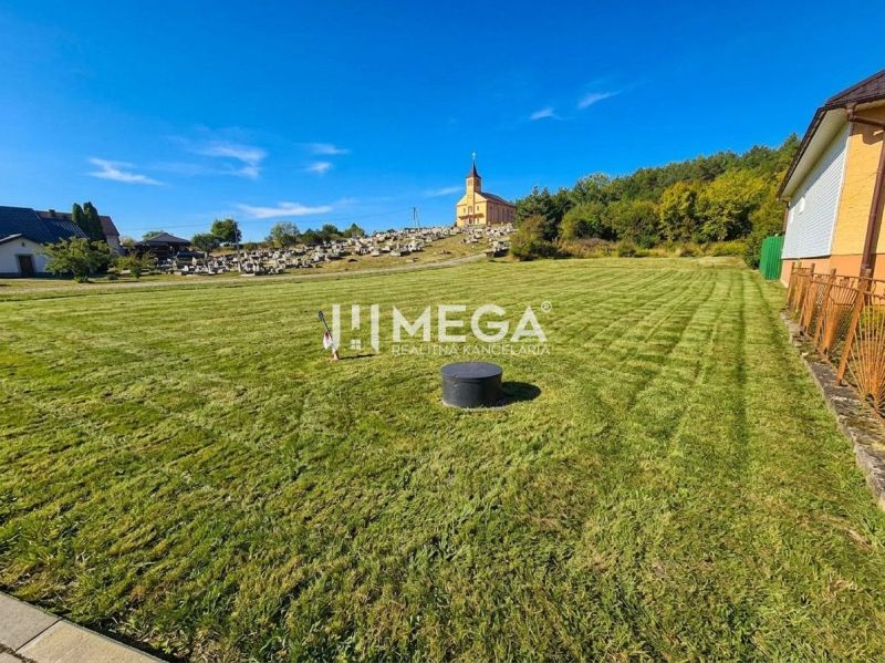Pozemky k bydlení ve Slovenské Volové s kostelem a hřbitovem v pozadí.