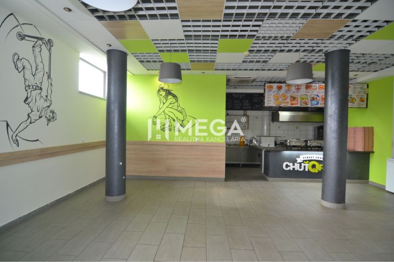 Interiér obchodních prostor s výzdobou na stěnách a otevřenou kuchyní.