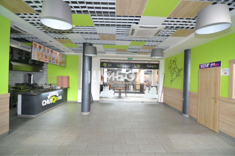 Obchodní prostory s jídelním pultem, podlaha s dřevěným dekorem, pestré interiérové prvky.