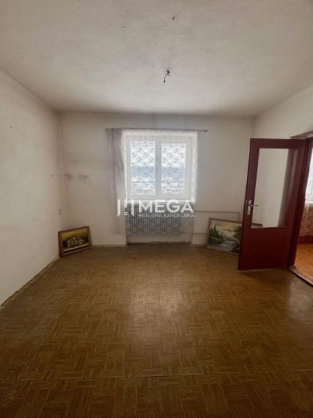 Pokoj v rodinném domě s podlahou s dřevěným dekorem a obrazy opřenými o stěnu.